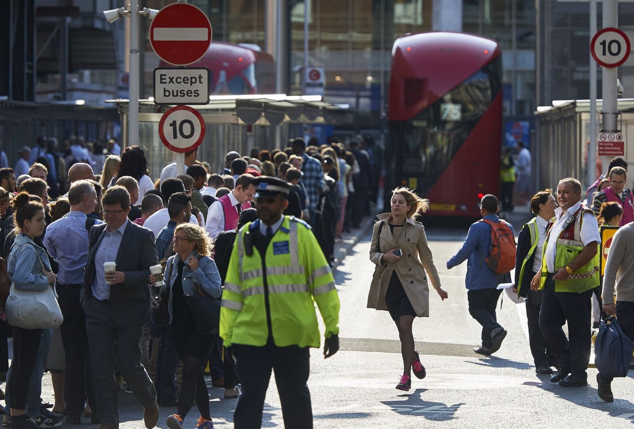 Early morning commuters form lines to board buses at Victoria Station.