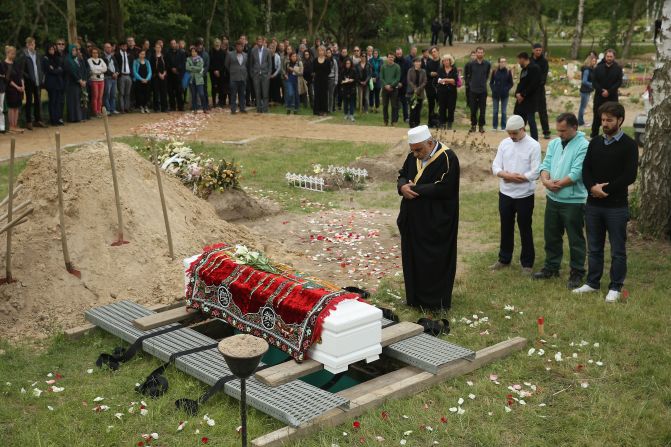 An imam leads a memorial service while standing next to a coffin, which, according to an artist group spokesman, contains the body of a female Syrian refugee who drowned in the Mediterranean in her attempt to reach Europe, in a reburial at Gatow cemetery on June 16, 2015 in Berlin, Germany. A German artist group called 'Political Beauty' ('Politische Schoenheit'), which had led the exhumation of the woman's body from Italy, organized the event as a form of protest against European Union refugee policy.