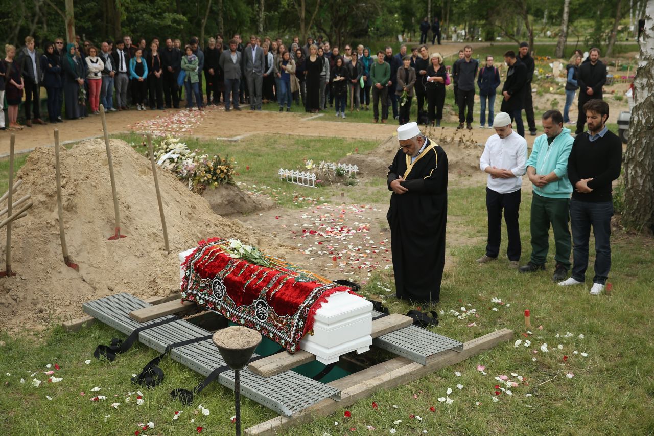An imam leads a memorial service while standing next to a coffin, which, according to an artist group spokesman, contains the body of a female Syrian refugee who drowned in the Mediterranean in her attempt to reach Europe, in a reburial at Gatow cemetery on June 16, 2015 in Berlin, Germany. A German artist group called 'Political Beauty' ('Politische Schoenheit'), which had led the exhumation of the woman's body from Italy, organized the event as a form of protest against European Union refugee policy.