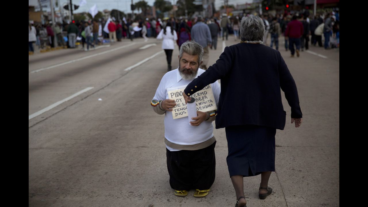 A beggar asks for donations near a site in Santa Cruz where people were gathering to see the Pope pass by on July 9.