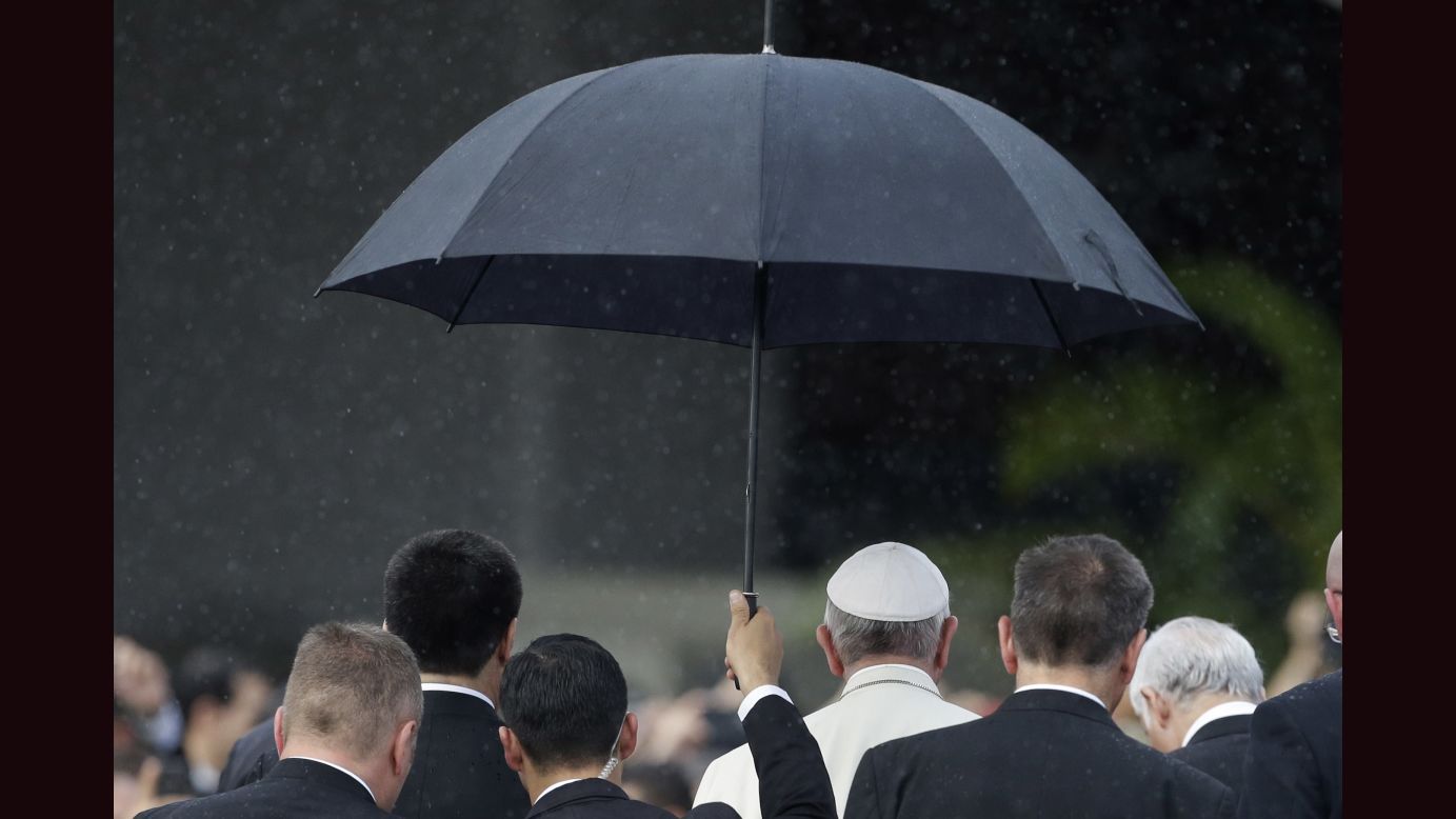 A member of the security detail holds an umbrella over Pope Francis upon his arrival in Asuncion on Friday, July 10. 