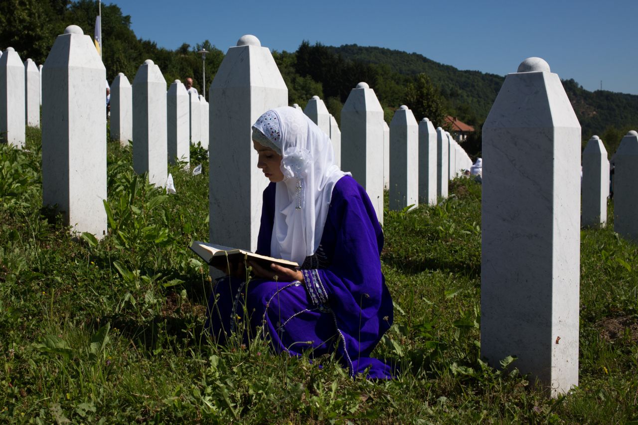 A girl reads the Quran at the site of her father's grave.