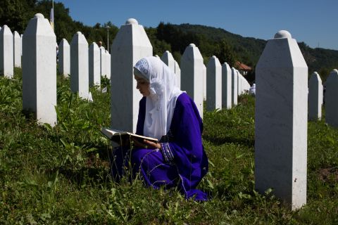 A girl reads the Quran at the site of her father's grave. 