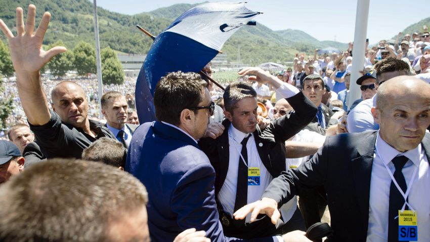 Bodyguards try to protect Serbian Prime Minister Aleksandar Vucic (behind umbrella) from stones hurled at him by an angry crowd at the Potocari Memorial Center, near the eastern Bosnian town of Srebrenica on July 11, 2015. Tens of thousands of people gathered in Srebrenica on July 11 to commemorate the 20th anniversary of the massacre of thousands of Muslims in the worst mass killing in Europe since World War II. Serbian Prime Minister Aleksandar Vucic was forced to leave the Srebrenica memorial when the crowd started to chant 'Allahu Akbar' (God is Great) and to throw stones. AFP PHOTO / DIMITAR DILKOFF (Photo credit should read DIMITAR DILKOFF/AFP/Getty Images)