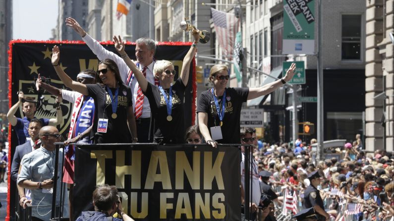 U.S. soccer player Megan Rapinoe holds up the Women's World Cup trophy as teammate Carli Lloyd, left, and head coach Jill Ellis, right, wave to fans during <a href="index.php?page=&url=http%3A%2F%2Fwww.cnn.com%2F2015%2F07%2F10%2Fus%2Fgallery%2Fus-soccer-team-parade%2Findex.html" target="_blank">a parade in New York City</a> on Friday, July 10. Behind Rapinoe is New York Mayor Bill de Blasio. 