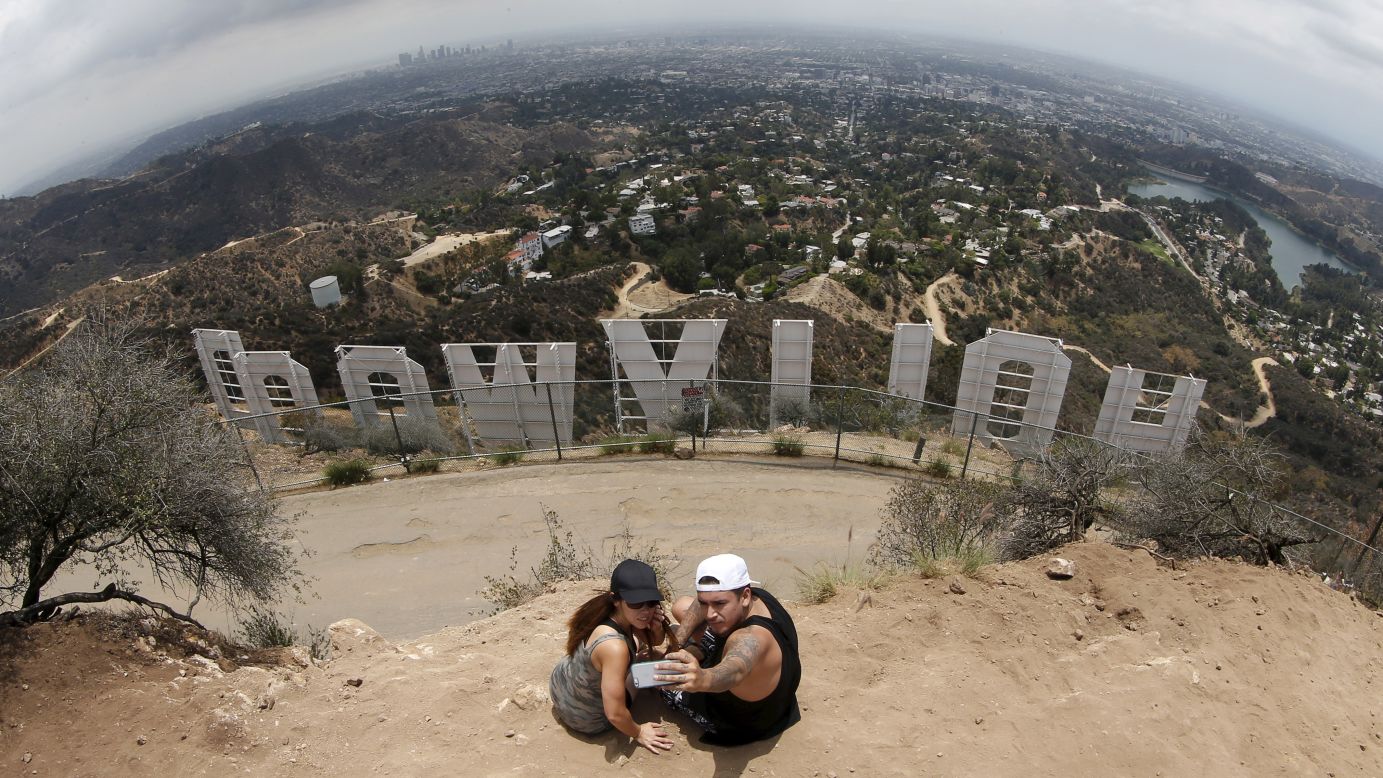 Two people take a selfie behind the famous Hollywood sign in Los Angeles on Thursday, July 9.
