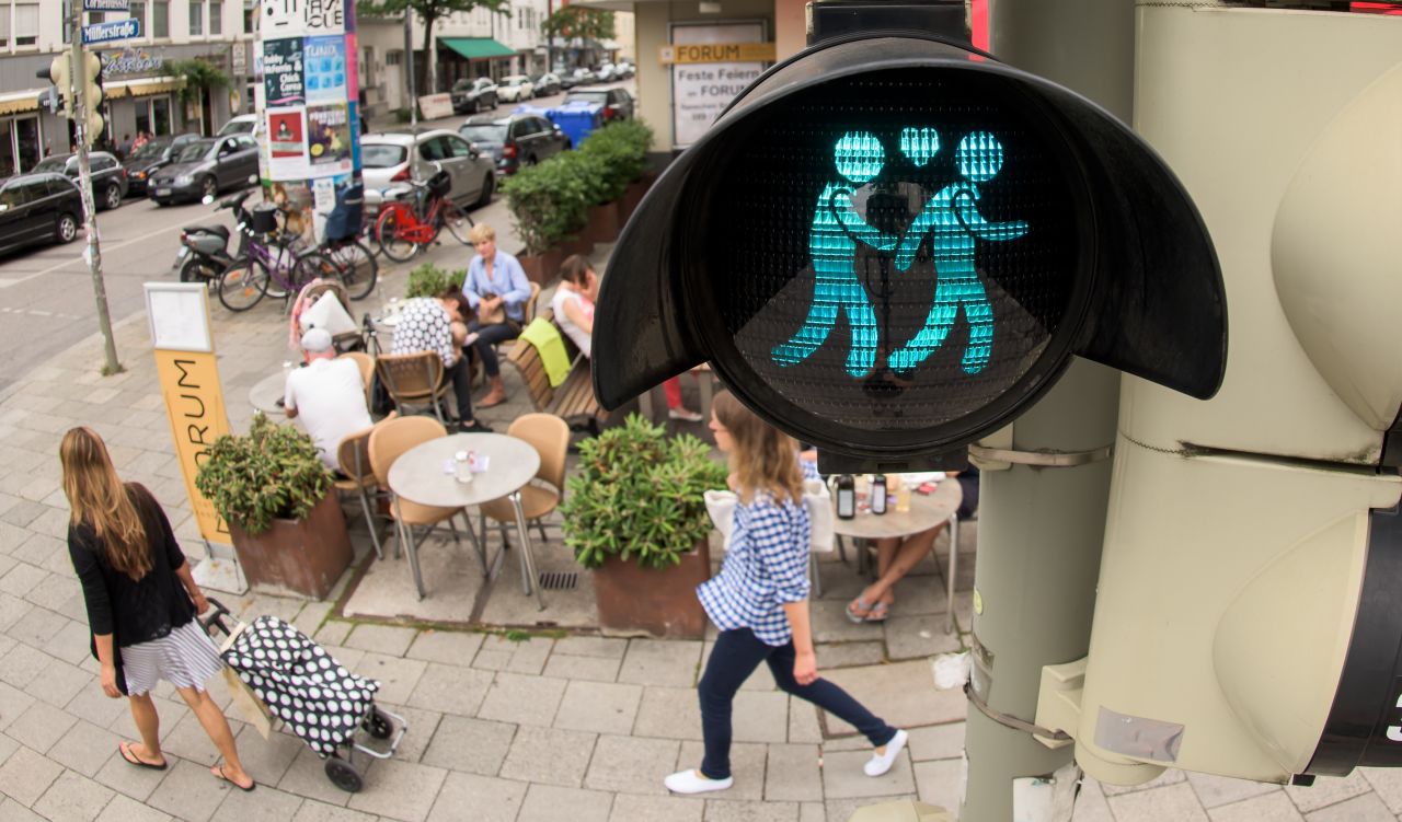 A pedestrian crossing signal shows a same-sex male couple at a junction in Munich on July 14. The figures glow in red and green at pedestrian crosswalks, showing both female and male couples.