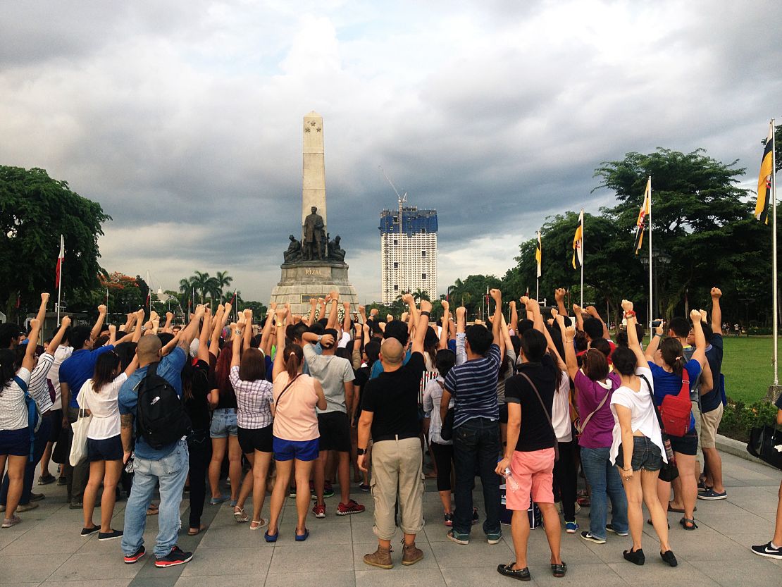 Celdran encourages tour-goers to shake their fists at the half-finished Torre de Manila building that's "photobombing" the historic Rizal Monument.