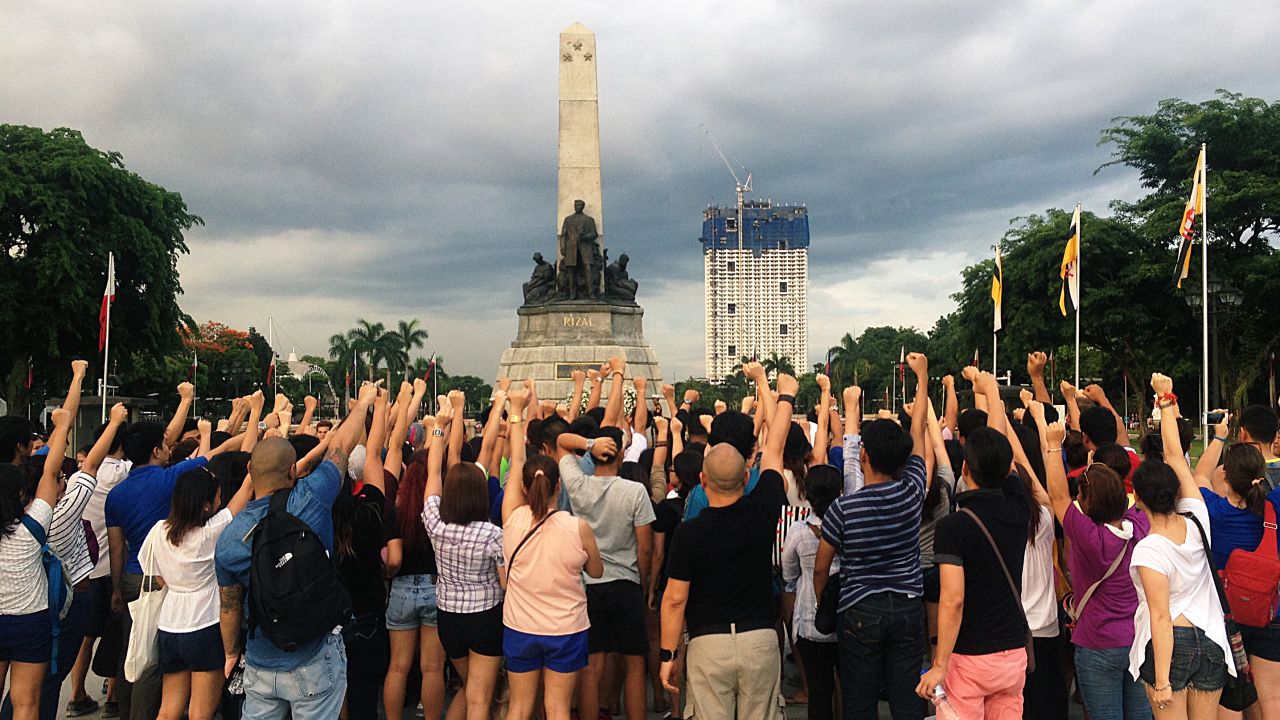 Celdran encourages tour-goers to shake their fists at the half-finished Torre de Manila building that's "photobombing" the historic Rizal Monument.