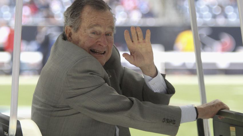 Caption:HOUSTON, TX - DECEMBER 01: Former U.S. President George H.W. Bush waves during the game between the New England Patriots and the Houston Texans at Reliant Stadium on December 1, 2013 in Houston, Texas. (Photo by Bob Levey/Getty Images)