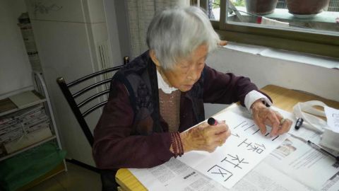 Zhao Shunjin practices writing her neighborhood's name.
