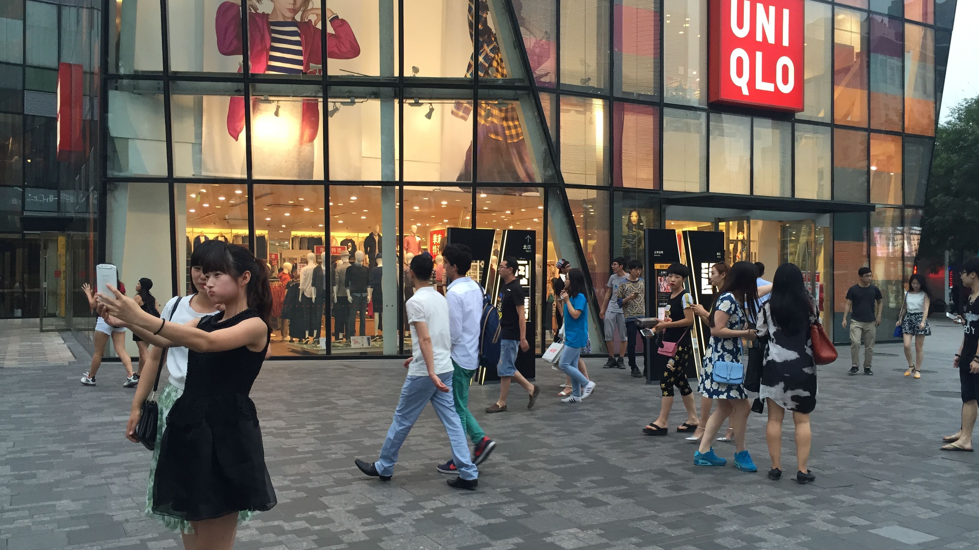 Two women take a selfie outside the Uniqlo store in Beijing on Wednesday, July 15. The store has gained notoriety after a viral sex video was shot inside. 