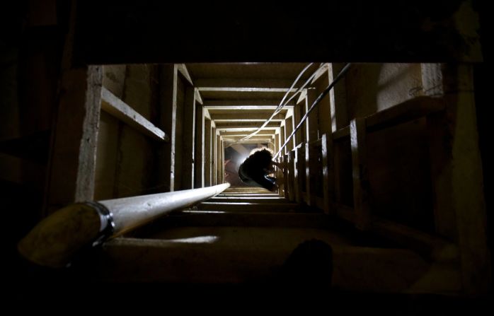 A journalist climbs a ladder to get out of the tunnel that authorities say Guzman used to escape.