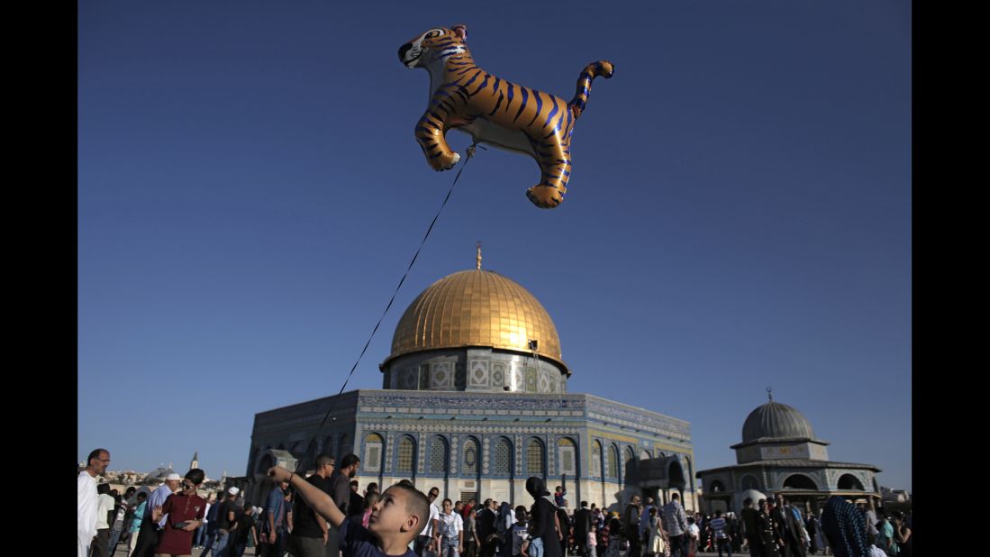 A Palestinian boy walks with a tiger balloon in front of the Dome of the Rock at the Al-Aqsa Mosque compound in Jerusalem's Old City.