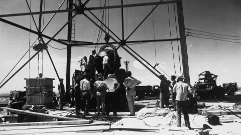 Workers in New Mexico attach a bomb to a tower two days before its successful test in July 1945.