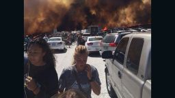 People flee their vehicles after being stopped on I-15 near San Bernardino, California, by a wildfire that jumped onto the highway, torched numerous vehicles and caused injuries.