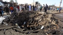 Iraqi men look at a crater left by a massive suicide car bomb attack carried out Friday in Khan Bani Saad.