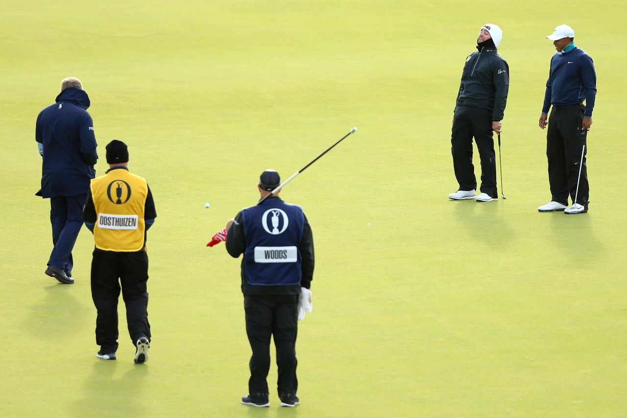 Louis Oosthuizen and Tiger Woods laugh as their balls move due to high winds on the 13th green before play is suspended during the second round at St. Andrews.