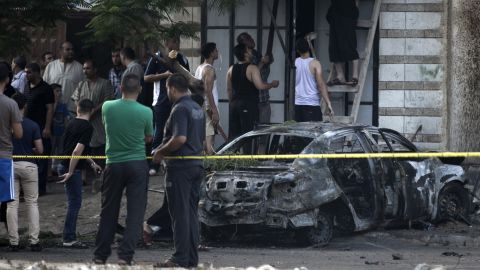 Palestinians gather around a burnt-out car in Gaza City on July 19, 2015, after explosions destroyed five cars in Gaza belonging to members of Hamas and Islamic Jihad, witnesses and a security source said.