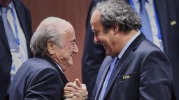 Caption:FIFA President Sepp Blatter (Foreground-L) shakes hands with UEFA president Michel Platini after being re-elected following a vote to decide on the FIFA presidency in Zurich on May 29, 2015. Sepp Blatter won the FIFA presidency for a fifth time after his challenger Prince Ali bin al Hussein withdrew just before a scheduled second round. AFP PHOTO / MICHAEL BUHOLZER (Photo credit should read MICHAEL BUHOLZER/AFP/Getty Images)