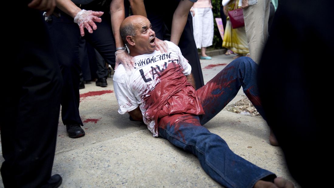 A demonstrator covered in red paint is detained after the flag-raising ceremony at the Cuban embassy in Washington.