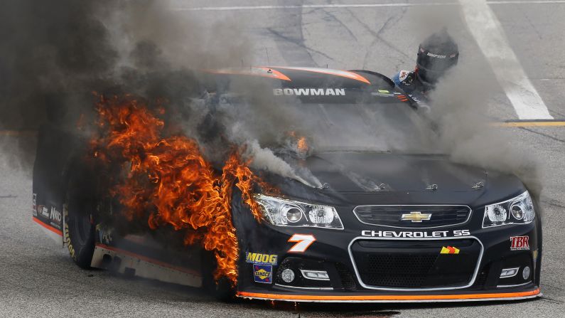 NASCAR driver Alex Bowman climbs out of his car after his front tire caught on fire Sunday, July 19, in Loudon, New Hampshire. Bowman was unharmed.