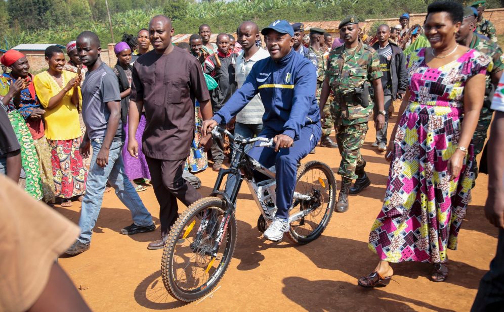 Nkurunziza is accompanied by first lady Denise Bucumi Nkurunziza, right, as he arrives on a bicycle to cast his vote in Ngozi, Burundi, on Tuesday, July 21.