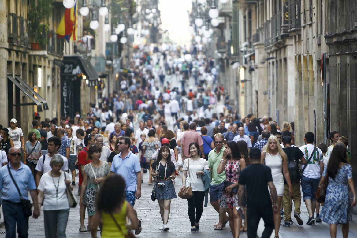 People stroll down Ferran street in downtown Barcelona on June 28, 2015. While tourism has helped boost GDP, Barcelona's new mayor, Ada Colau, has vowed to protect and regulate neighborhoods overrun by rowdy tourists, unlicensed rentals and spikes in prices.
