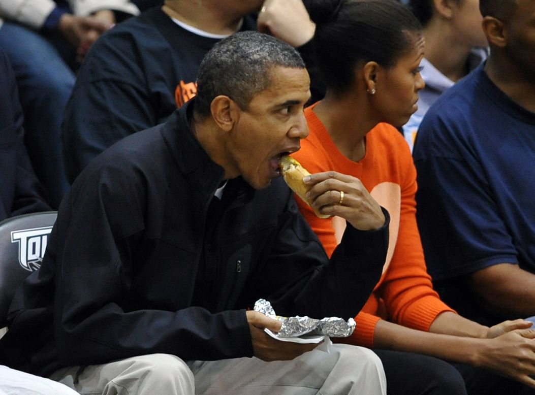 Obama downs a dog as he and first lady Michelle Obama watch the Oregon State vs Towson basketball game in Towson, Maryland, on November 26, 2011. 