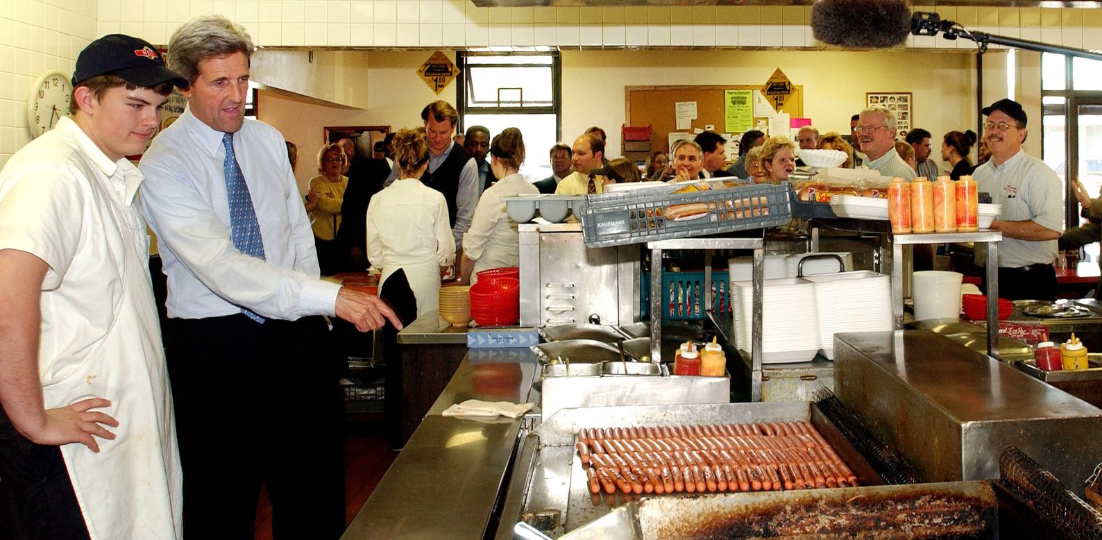 Then-Democratic presidential hopeful Sen. John Kerry of Massachusetts, right, speaks with a cook at the hot dog grill during an impromptu stop at the Brighton Hot Dog Shoppe on April 26, 2004, in Beaver, Pennsylvania.