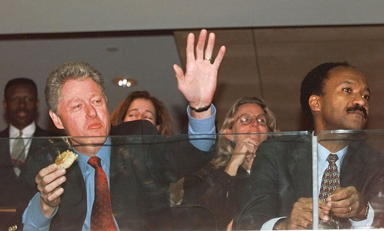 Then-President Bill Clinton, left, enjoys a hot dog with then-Director of the Office of Management and Budget Franklin Raines on December 2, 1997, at the MCI Center in Washington. 