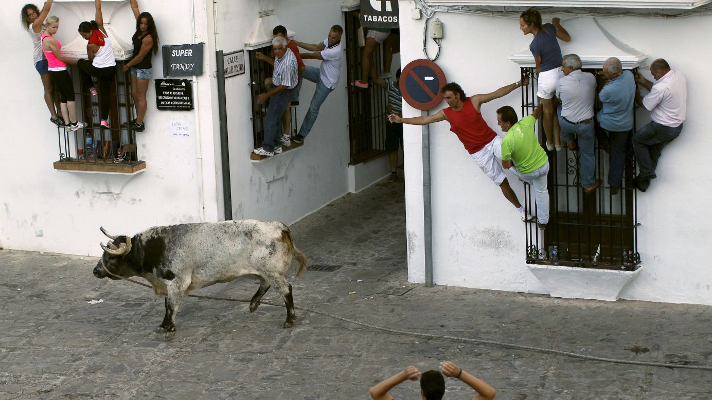 People in Grazalema, Spain, avoid a bull during the Toro de Cuerda festival on Monday, July 20. During the festival, a long rope restrains bulls as they run through the village's streets.