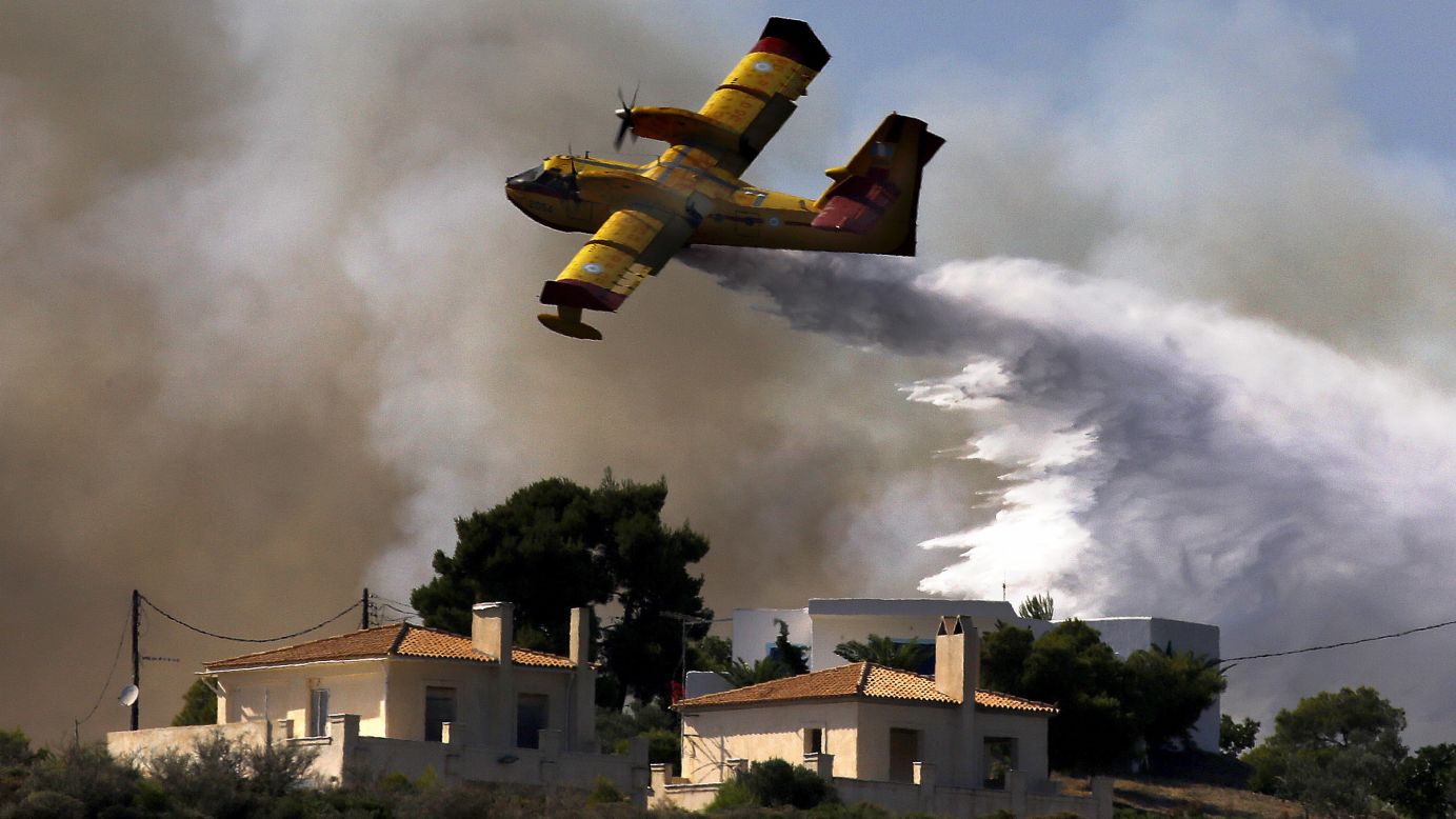 A plane drops water over a wildfire threatening holiday homes in the Greek village of Costa on Monday, July 20. 