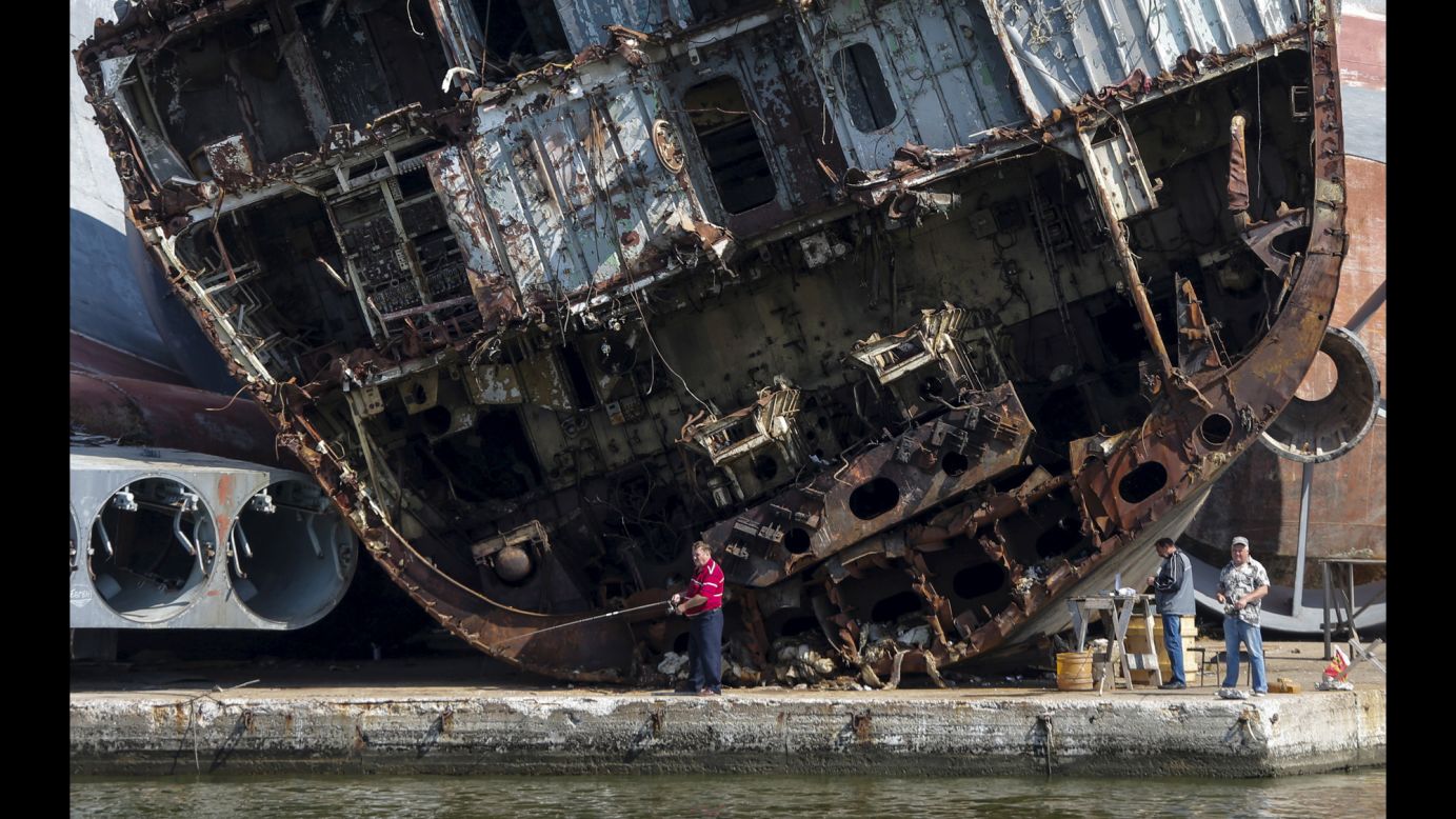 Men fish in front of ship remains at the Russian fleet base in Baltiysk on Sunday, July 19.