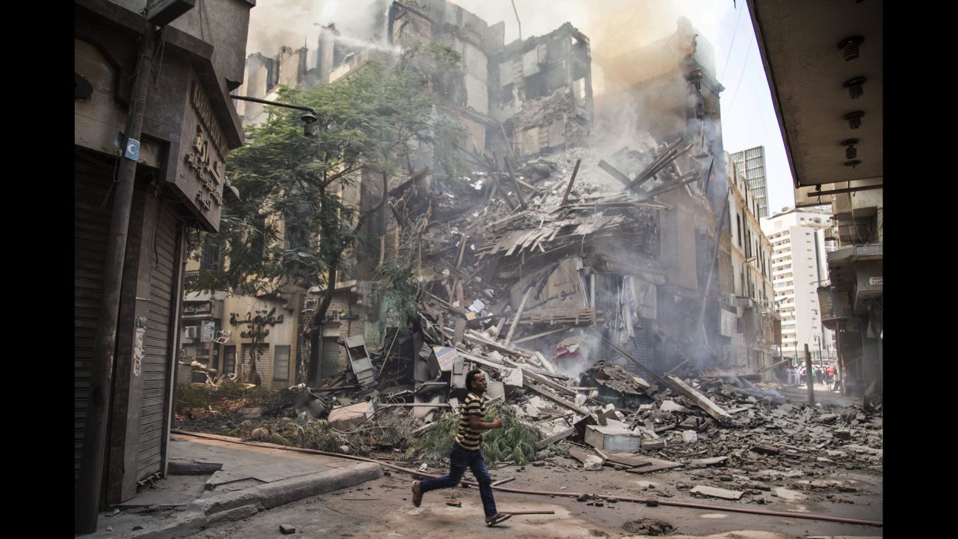 A man runs past the remains of a burning building in downtown Cairo on Monday, July 20. According to local reports, at least 17 fire engines were dispatched to the scene.
