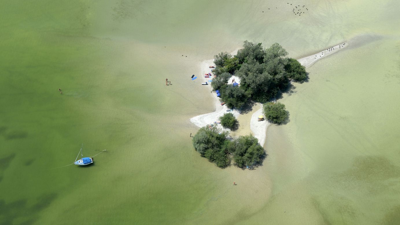 People enjoy sunny weather on a small island in Lake Ammer, near Munich, Germany, on Tuesday, July 21.