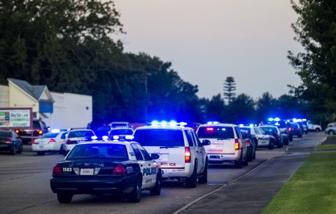 Lafayette Police Department and Louisiana State Police units block an entrance road near the scene of the shooting.