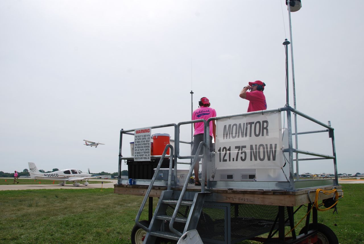 Air traffic controllers use special mobile platforms to direct airplane departures from the center of the Oshkosh airfield.