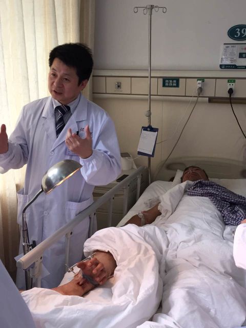 Dr. Tang Juyu, left, of the Xiangya Hospital in Changsha, in central China, led a surgical team that grafted a patient's severed hand to his leg. The patient, an industrial worker identified as Mr. Zhou, are shown following the grafting operation.