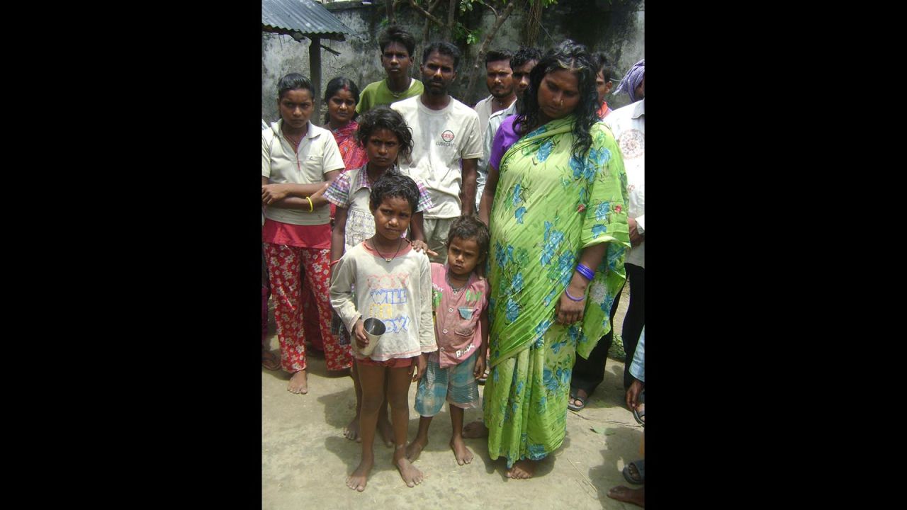 Jivan's mother dressed in green, stands with family members. According to testimony given to police, her son was lured away from their village with the promise of biscuits and the equivalent of 49 cents.