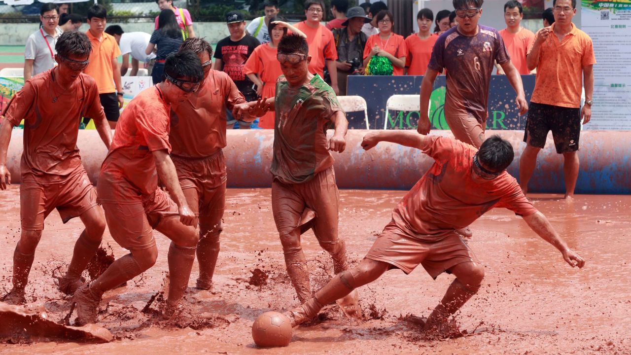 Players compete for the ball during a game of swamp soccer in Beijing on Friday, July 24.