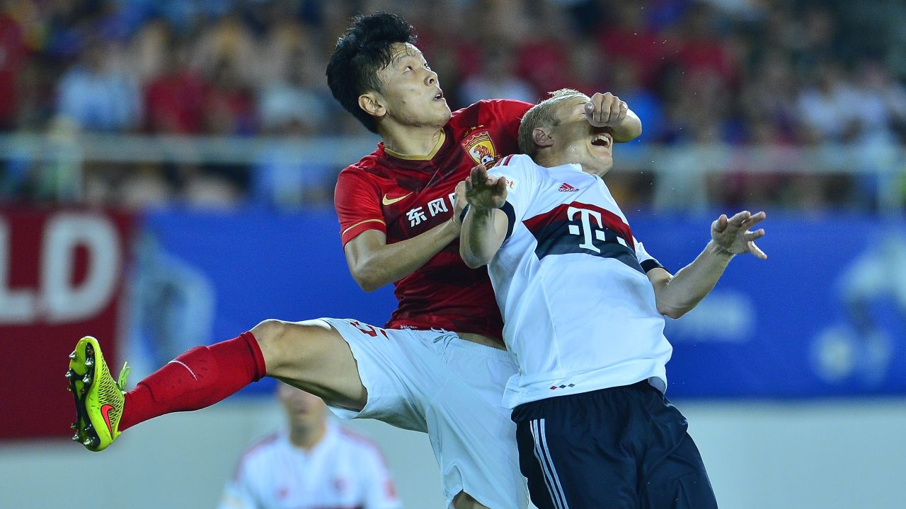 Zou Zheng, a soccer player with Chinese club Guangzhou Evergrande, tussels with Bayern Munich's Sebastian Rode, right, during an exhibition match in Guangzhou, China, on Thursday, July 23.