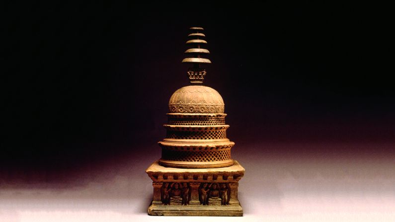 Cremated relics of the Buddha such as his tooth, strands of his hair or bones were scattered in different dome-shaped structures called stupas. Inspired by simple burial mounds, these were at the heart of the Buddhist landscape that spread across India.<br /><br />Stupas were decorated with stories of the Buddha's path. <br /><br />"You would contemplate the images and think about your own path to enlightenment," says McCullough. <br /><br />Pilgrims and merchants flocked to these sites in the hope of gaining religious merit.<br /><br />This is an architectural prototype of a stupa. The circular lid could be removed to place a relic inside. Intricately carved, the bottom tier shows the Buddha deep in meditation with attendants on either side.