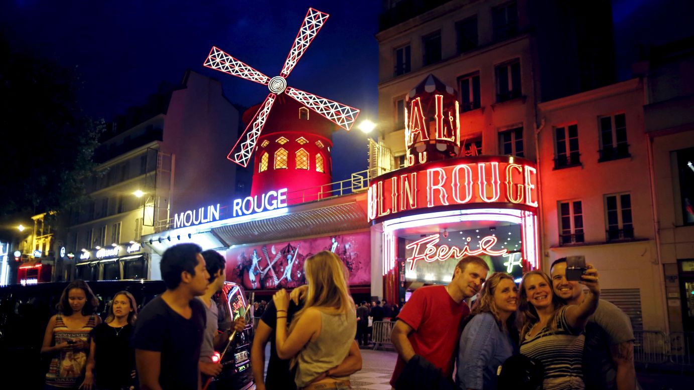 Tourists take a selfie in front of the Moulin Rouge cabaret in Paris on Friday, July 24.