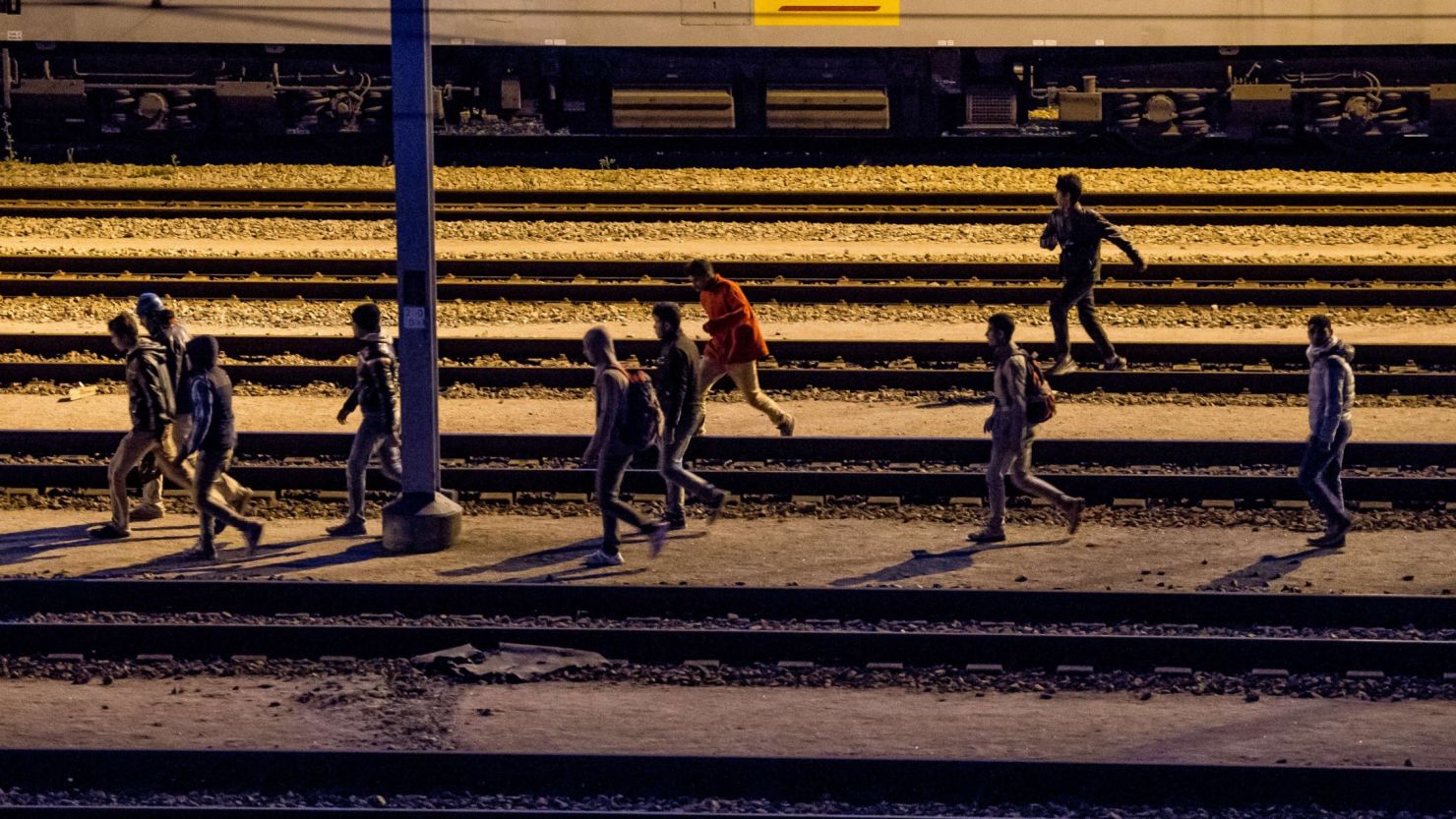 Migrants walk along railway tracks at the Eurotunnel terminal on July 28, 2015 in the Calais-Frethun station in the French port town of Calais.