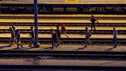 Migrants walk along railway tracks at the Eurotunnel terminal on July 28, 2015 in the Calais-Frethun station in the French port town of Calais.