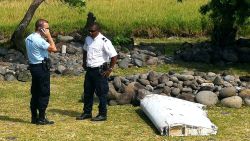 A policeman and a gendarme stand next to a piece of debris from an unidentified aircraft found in the coastal area of Saint-Andre de la Reunion, in the east of the French Indian Ocean island of La Reunion, on July 29, 2015. The two-metre-long debris, which appears to be a piece of a wing, was found by employees of an association cleaning the area and handed over to the air transport brigade of the French gendarmerie (BGTA), who have opened an investigation. An air safety expert did not exclude it could be a part of the Malaysia Airlines flight MH370, which went missing in the Indian Ocean on March 8, 2014. AFP PHOTO / YANNICK PITONYANNICK PITON/AFP/Getty Images