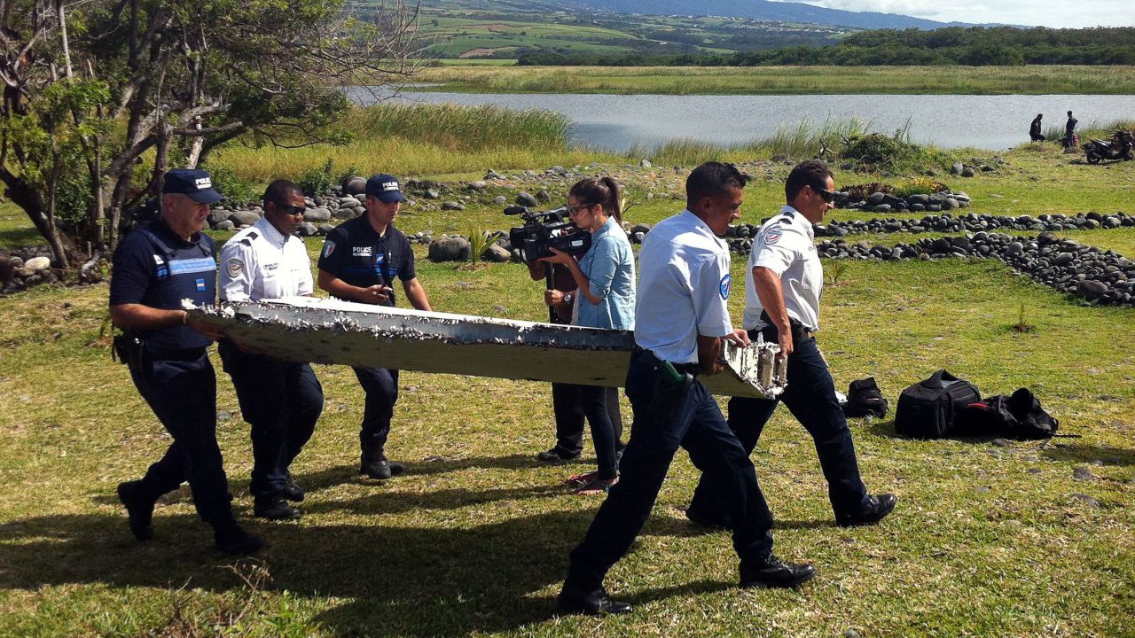 Police carry debris from an unidentified aircraft found in the coastal area of Saint-Andre de la Reunion, in the east of the French Indian Ocean island of La Reunion, on July 29, 2015. An air safety expert did not exclude it could be a part of the Malaysia Airlines flight MH370.