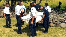 Police and gendarmes carry a piece of debris from an unidentified aircraft found in the coastal area of Saint-Andre de la Reunion, in the east of the French Indian Ocean island of La Reunion, on July 29, 2015. The two-metre-long debris, which appears to be a piece of a wing, was found by employees of an association cleaning the area and handed over to the air transport brigade of the French gendarmerie (BGTA), who have opened an investigation. An air safety expert did not exclude it could be a part of the Malaysia Airlines flight MH370, which went missing in the Indian Ocean on March 8, 2014. AFP PHOTO / YANNICK PITONYANNICK PITON/AFP/Getty Images
