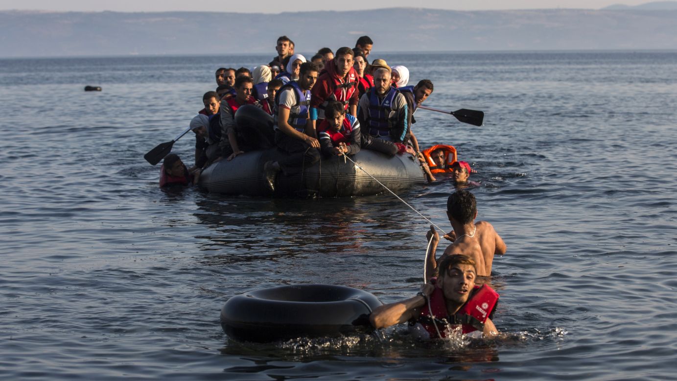 Two migrants pull a dinghy filled with Syrian and Afghan refugees as they arrive on the Greek island of Lesbos on Monday, July 27. Tens of thousands of migrants have arrived in Greece so far this year, overwhelming local authorities, aid groups say.